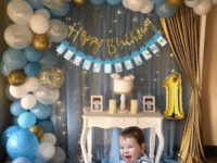 SpecialYou.in 1st Birthday Decoration Combo for Boys – Net Fabric Backdrop, Gold Number “1” Foil Balloon, 40ft Fairy Light, Confetti Balloons & Monthly Milestone Banner